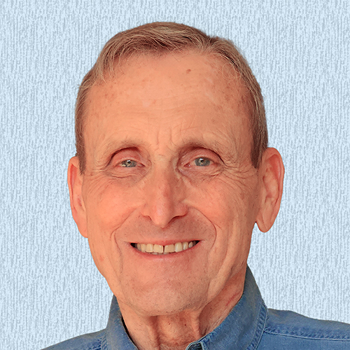 Photo of William Hicks, light blue background and smiling.